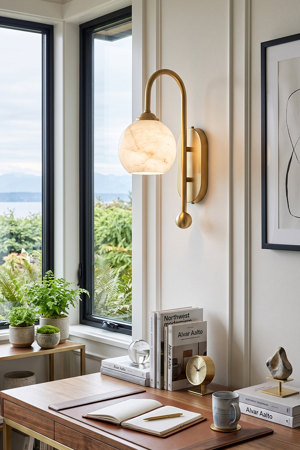 Seraphine Alabaster Globe Wall Sconce mounted on a wall beside a desk with a natural light setting.