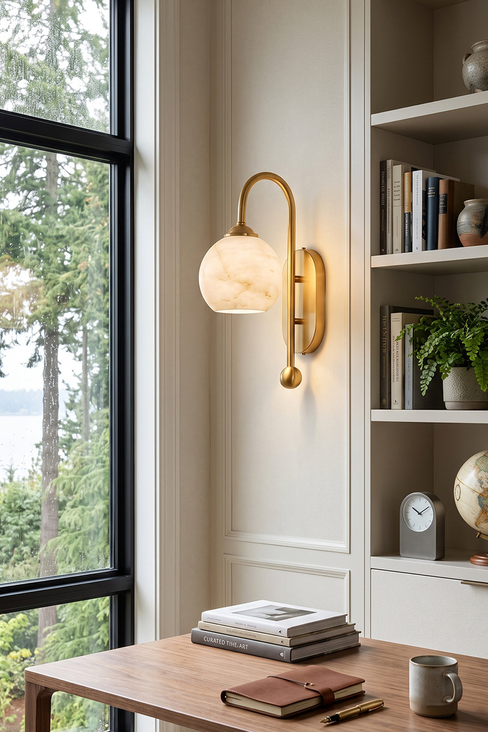 Seraphine Alabaster Globe Wall Sconce illuminating a modern interior with a curved gold arm and round alabaster globe.