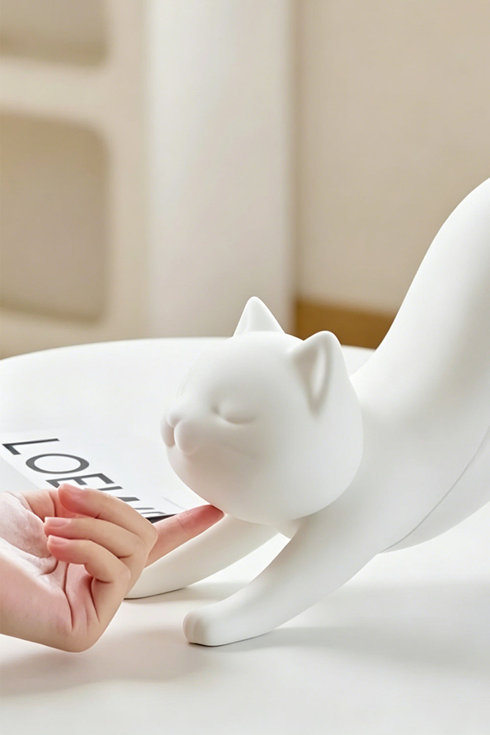 Interactive cat-shaped table lamp | white resin | hand touching cat head on desk | Samu Lamp