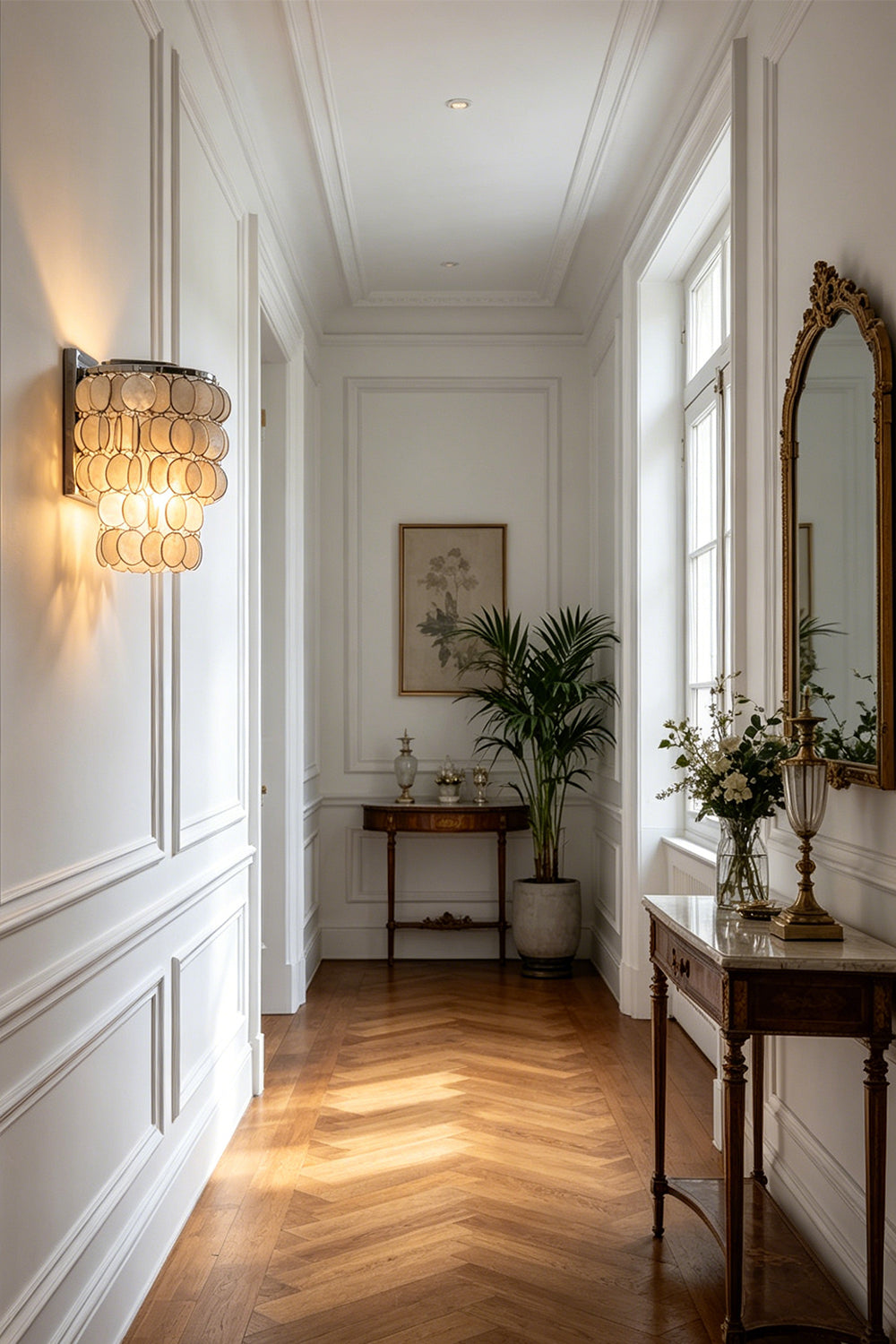 Shimmering Capiz shell wall sconce | Shell | Iron | Installed in a bright hallway with herringbone floors | Samu Lamp