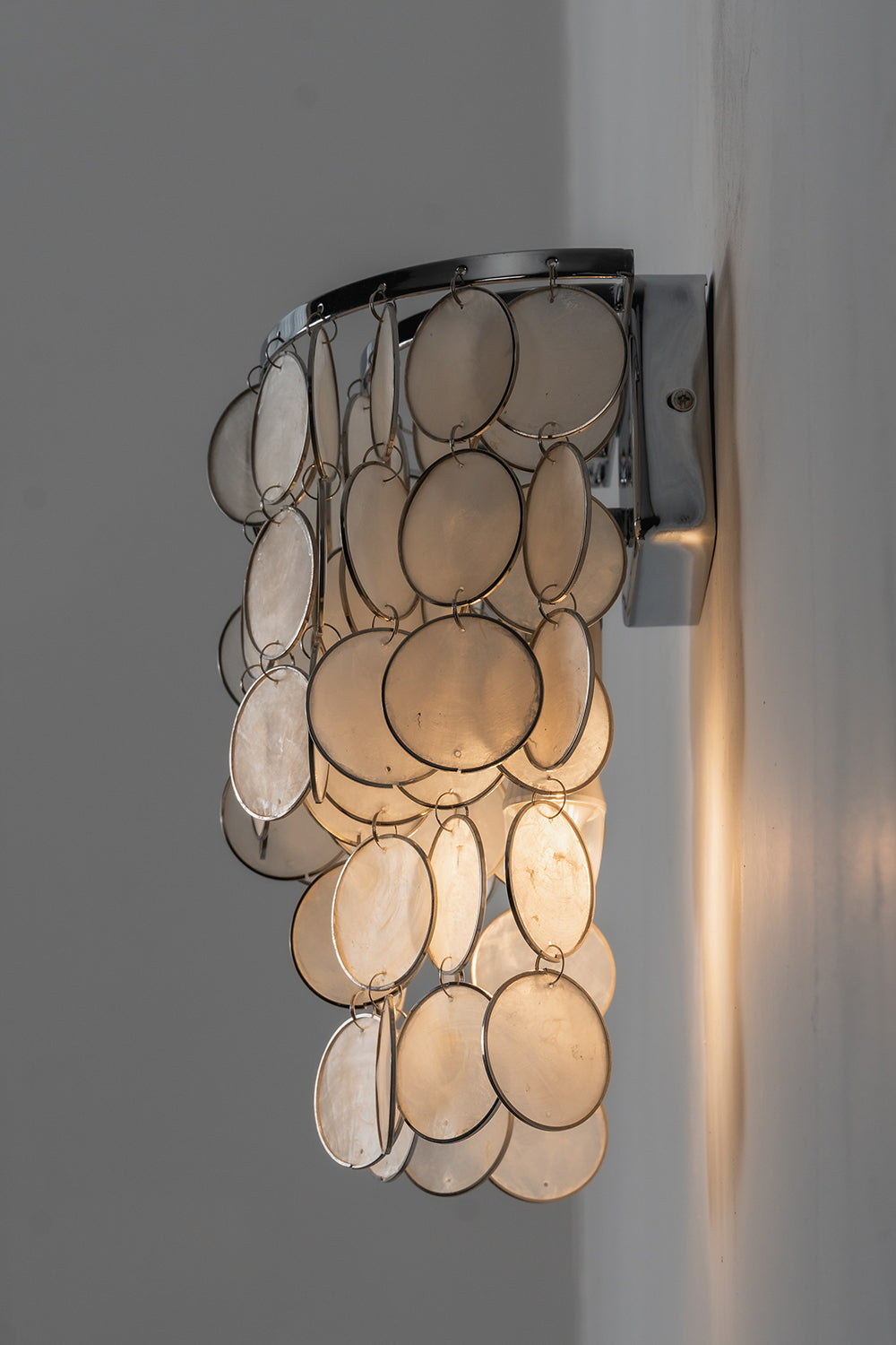 Side profile of Capiz shell wall lamp | Shell | Iron | Side view showing layered shell discs and metal bracket | Samu Lamp