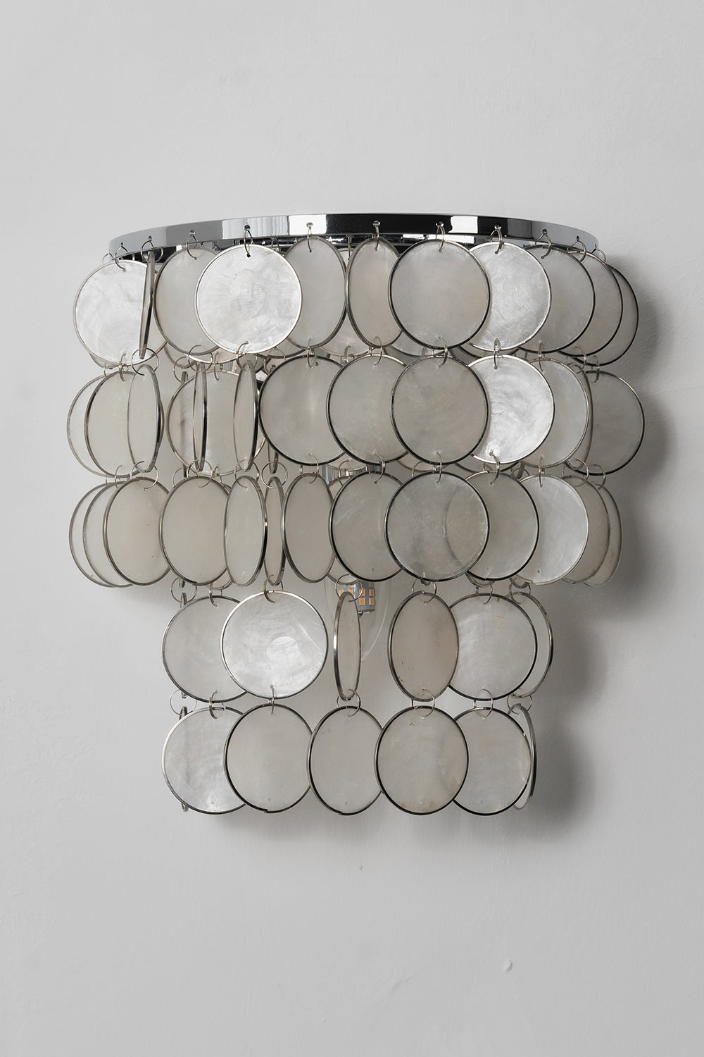 Unlit Shimmering Round Capiz Wall Lamp | Shell | Iron | Front product shot against a grey wall | Samu Lamp