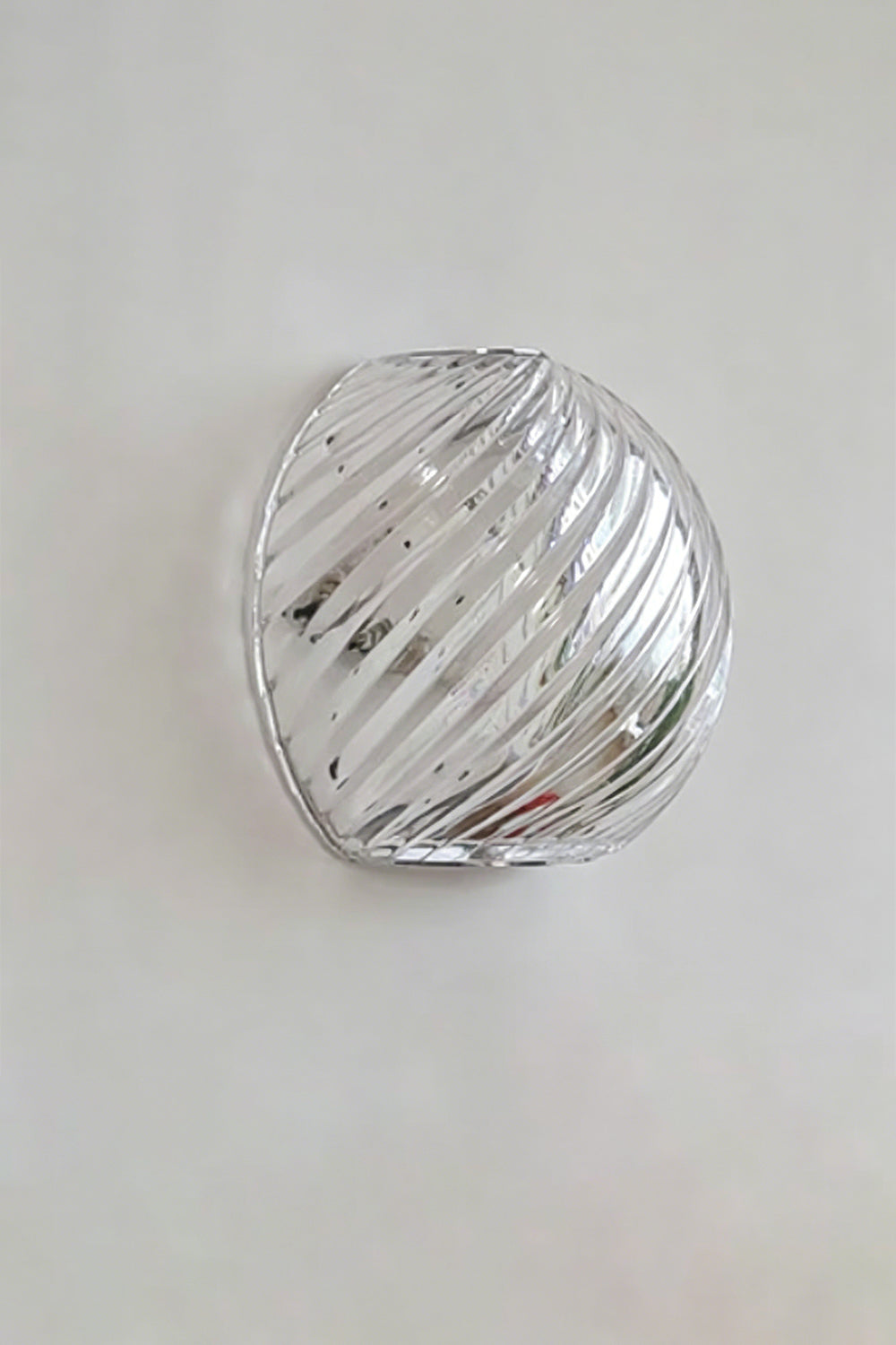 Silas Ribbed Glass Wall Sconce | Ribbed Glass, Metal | Studio unlit view of the clear silver ribbed glass finish variant showcasing its organic pebble silhouette against a plain backdrop | Samu Lamp