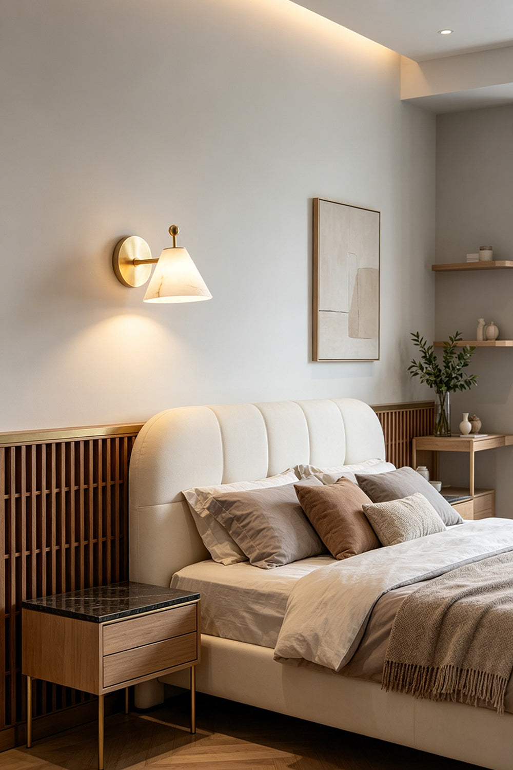 Solene Alabaster Cone Wall Sconce | Alabaster, Brass | Mounted as an elegant bedside accent light casting a warm downward glow above a wooden nightstand in a contemporary bedroom suite | Samu Lamp
