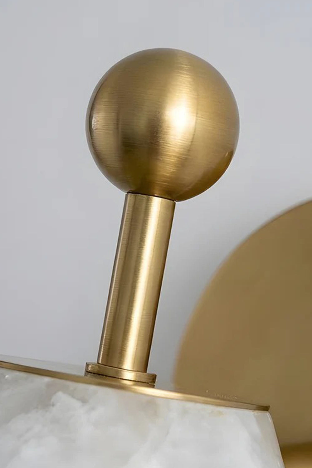 Solene Alabaster Cone Wall Sconce | Alabaster, Brass | Detailed close-up shot focusing on the top decorative brushed gold brass ball accent pin securing the alabaster cone stone shade | Detail shot | Samu Lamp
