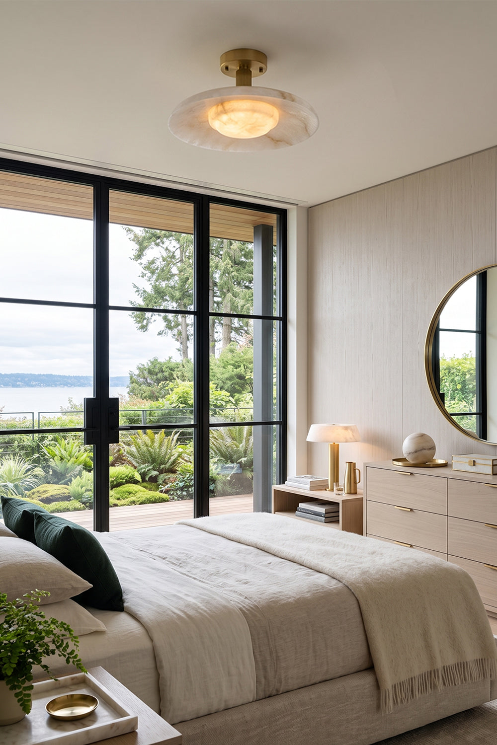 Solene Alabaster Round Ceiling Light | Bedroom Lighting | Installed as an elegant flush mount ceiling fixture casting a soft ambient glow in a contemporary white bedroom next to large glass sliding doors | Samu Lamp