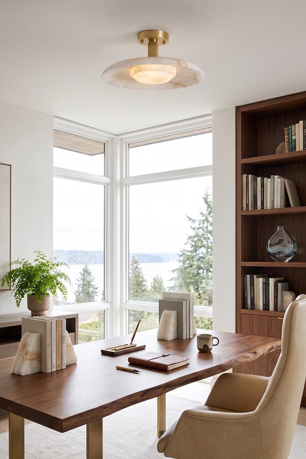 Solene Alabaster Round Ceiling Light | Office Ceiling Lamp | Providing warm overhead illumination in a bright home study space featuring a large wooden desk and scenic lake views through windows | Samu Lamp