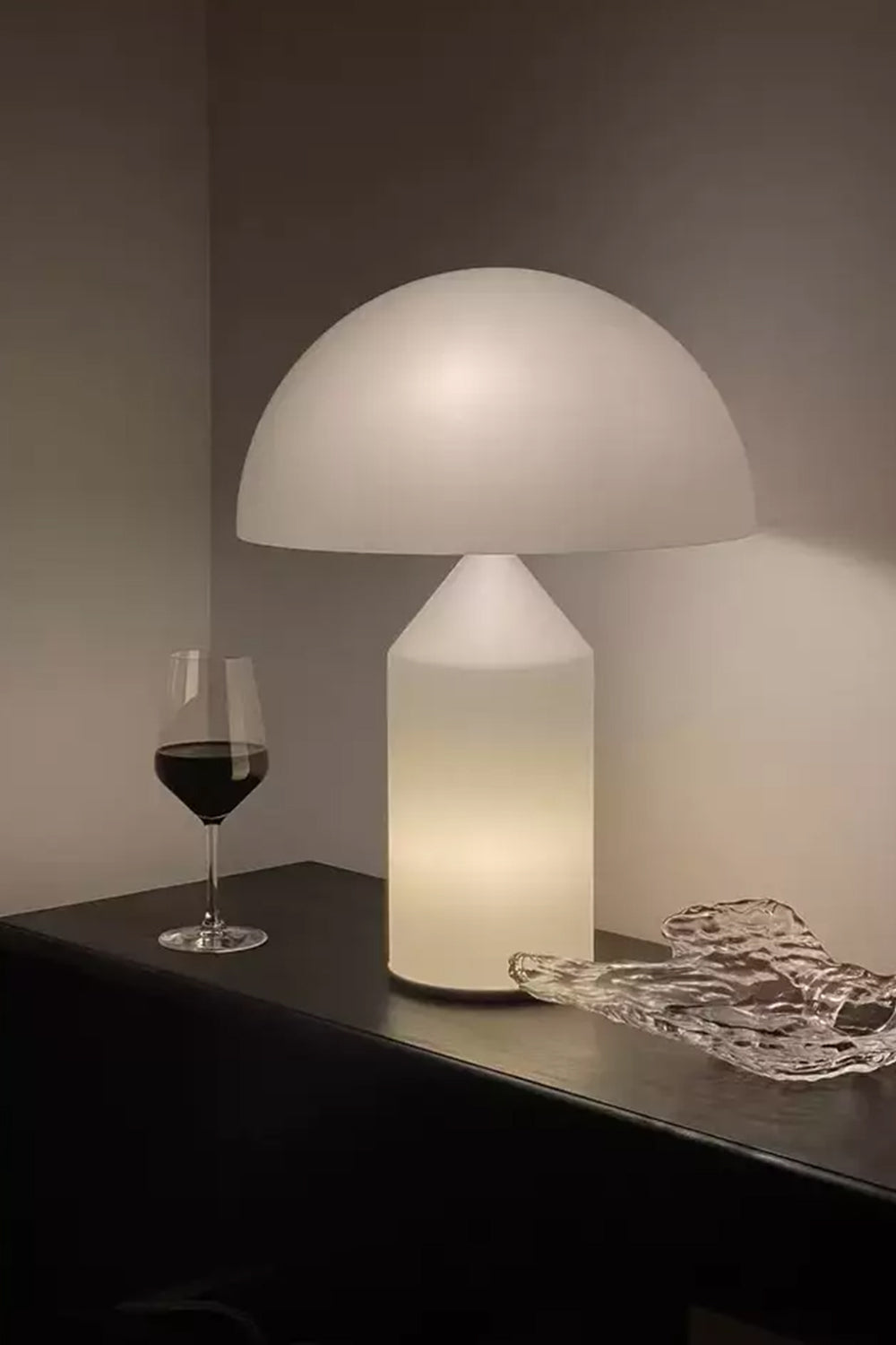 Solene Domed Glass Table Lamp | White Frosted Glass | Lit up on a dark shelf next to a glass of red wine creating a warm atmosphere | Samu Lamp
