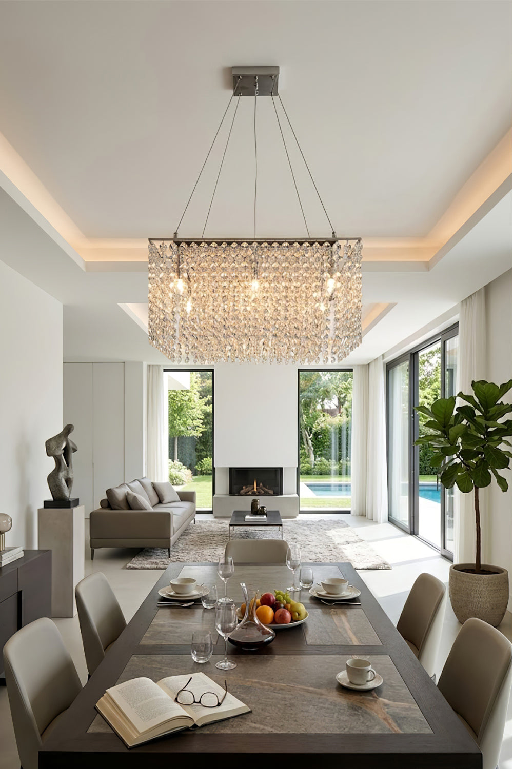 Sparkling crystal chandelier centered over a long dining table | Stainless Steel, Crystal | Elegant dining room with views of a garden and pool | Samu Lamp