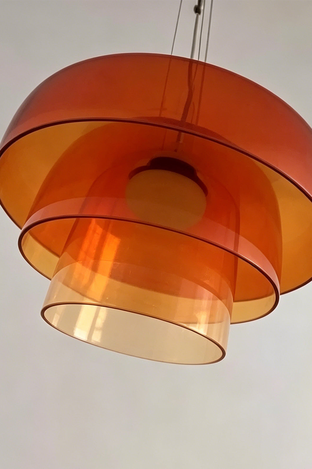 Stratum Layered Glass Pendant Light | Glass, Metal | Low-angle close-up highlighting the concentric tiered layers and smooth curved edges of the orange translucent glass | Detail shot | Samu Lamp
