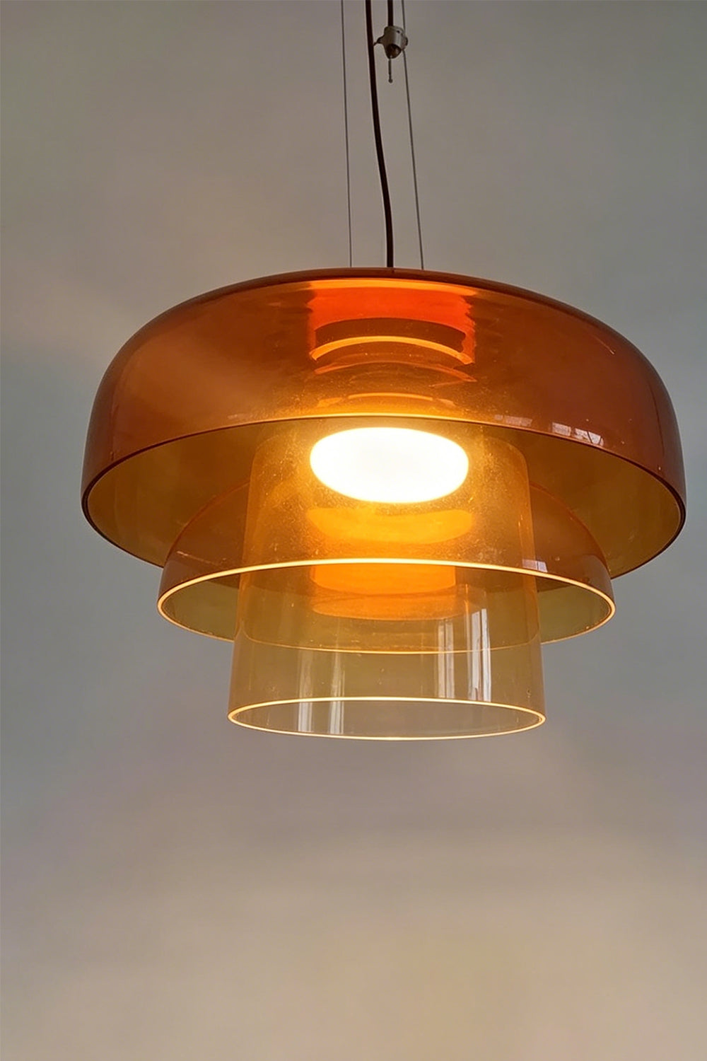 Stratum Layered Glass Pendant Light | Glass, Metal | Detailed frontal view of the illuminated orange glass layers showcasing its warm internal light source | Detail shot | Samu Lamp