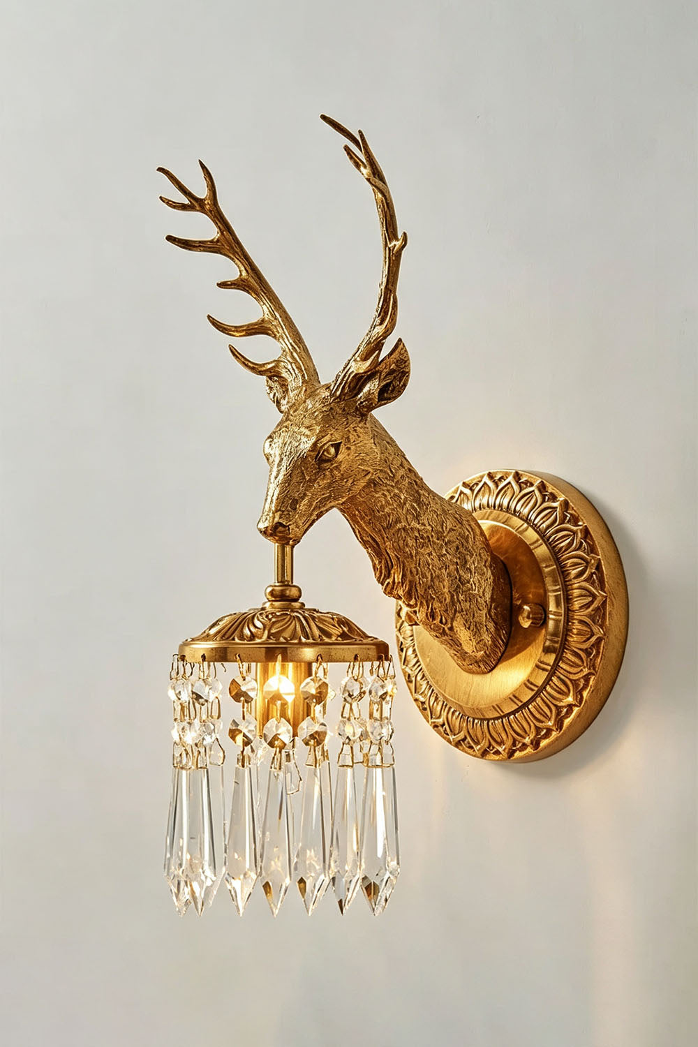 Sylvestre Cast Brass Stag Wall Sconce | Cast Brass and Crystal | Angled view glowing softly against a plain white wall | Samu Lamp