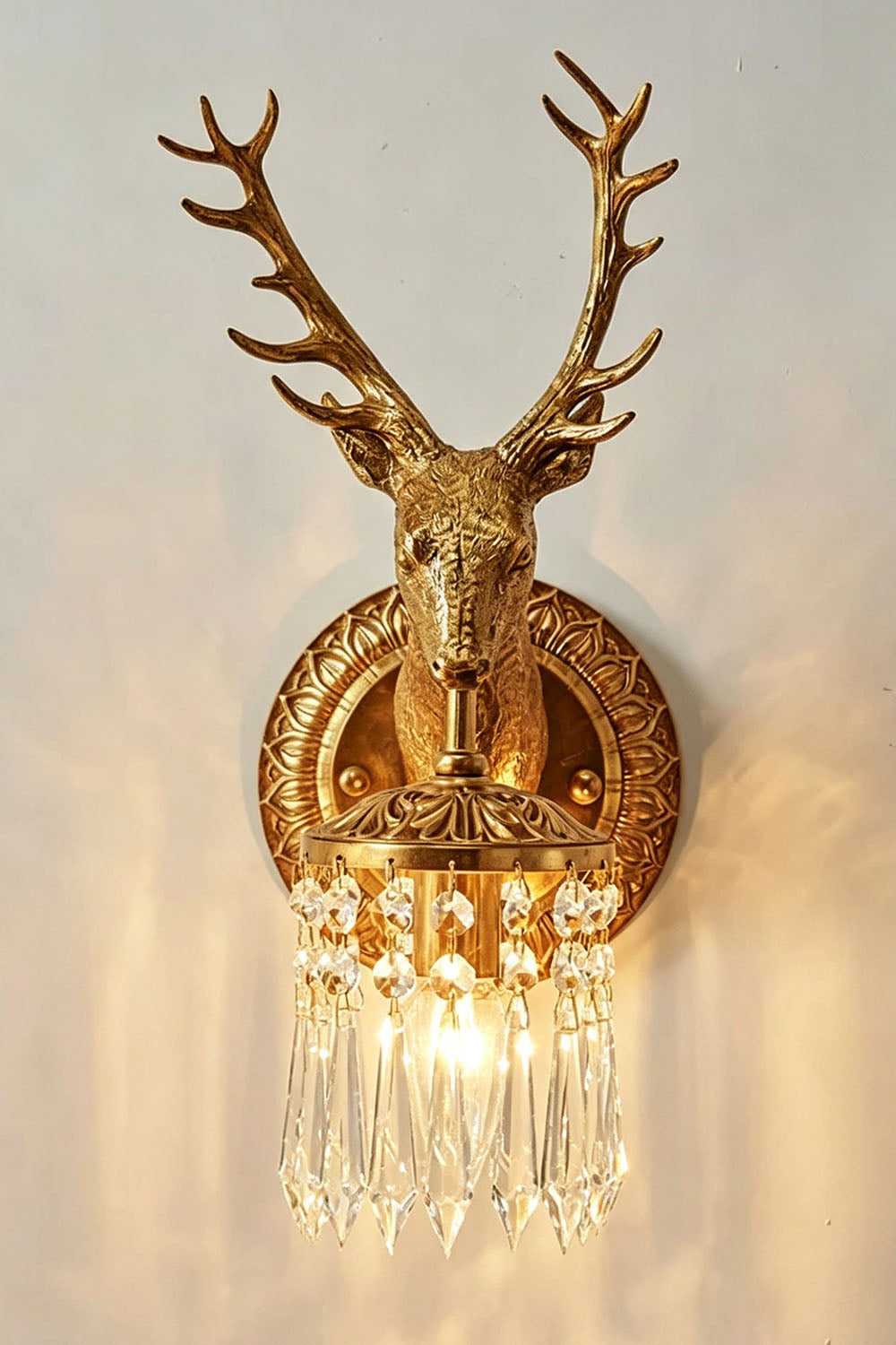 Sylvestre Cast Brass Stag Wall Sconce | Cast Brass and Crystal | Front illuminated view displaying warm light on a plain backdrop | Samu Lamp
