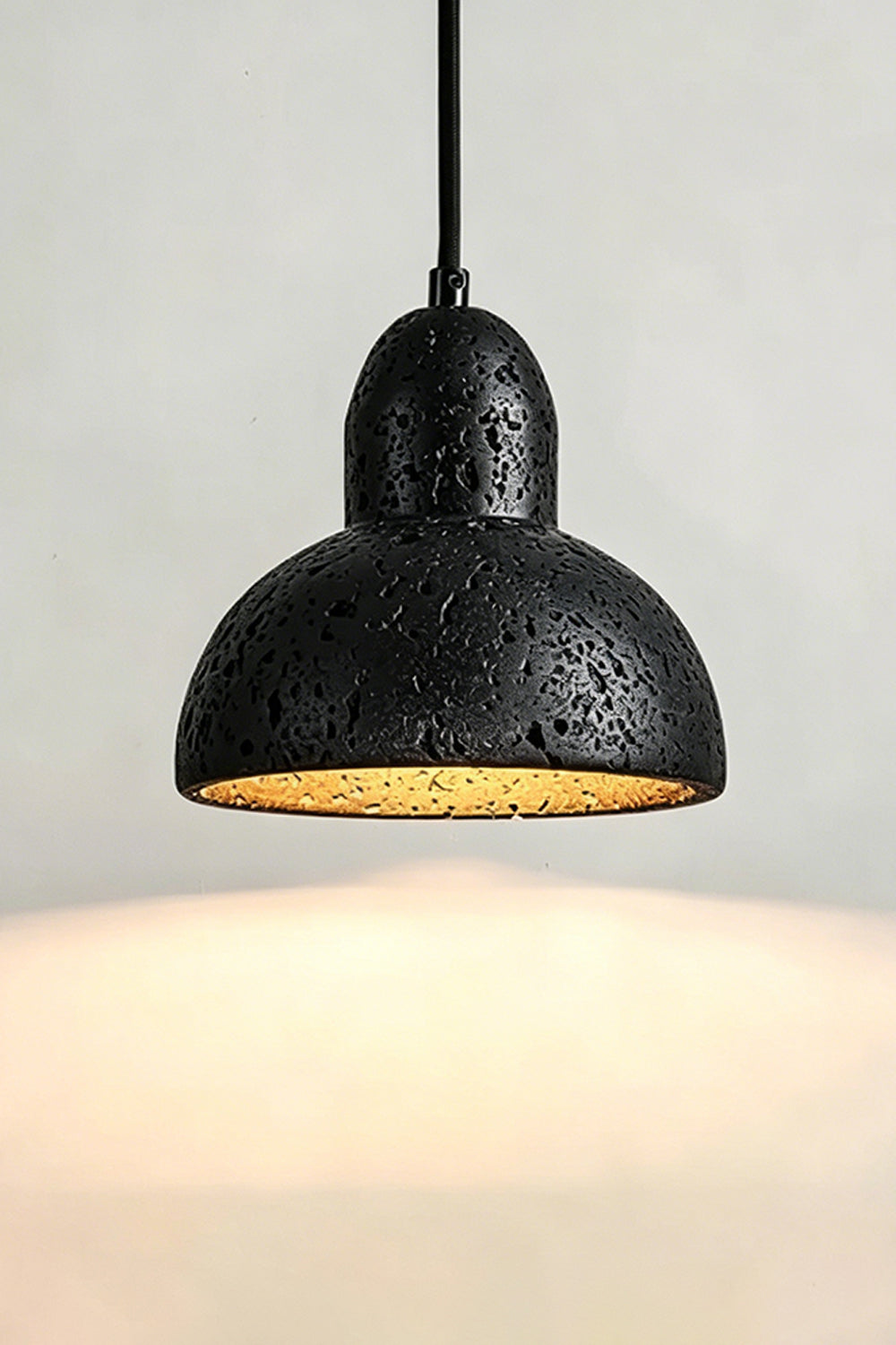 Lit Black Travertine Pendant Light | Black Travertine, Metal, Glass | Close-up showing warm upward and downward glow | Samu Lamp