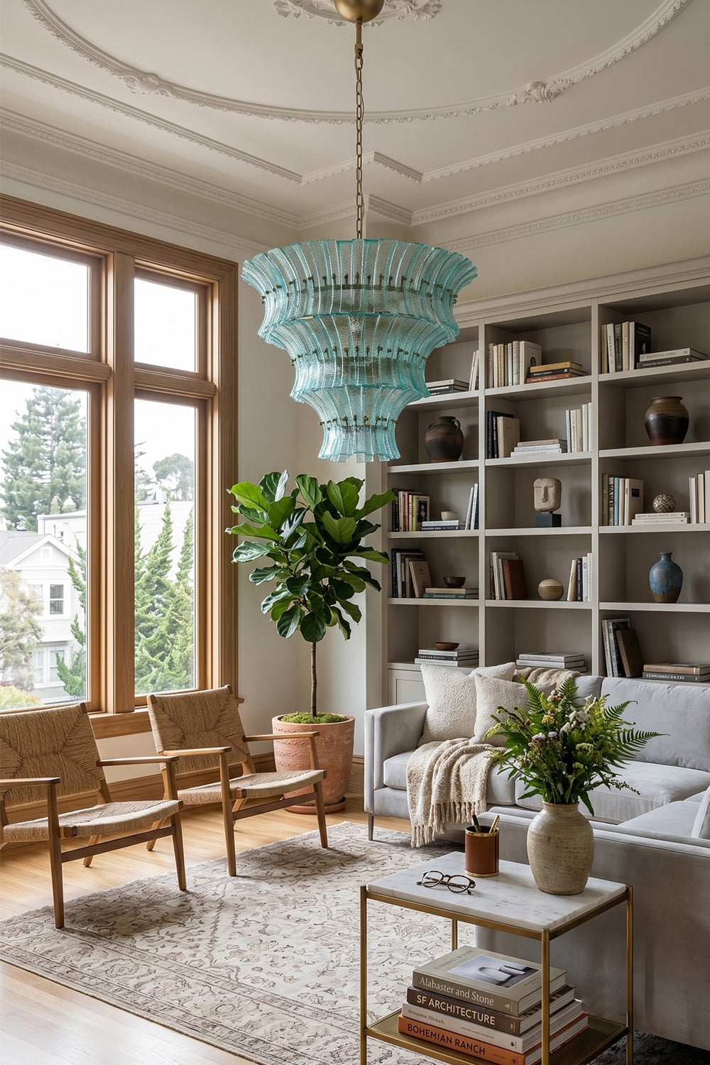 Thalassa Aquamarine Textured Glass Chandelier | Glass, Metal | Providing a cozy colorful glow in a contemporary living space decorated with built-in bookcases, white couches, and plants | Samu Lamp