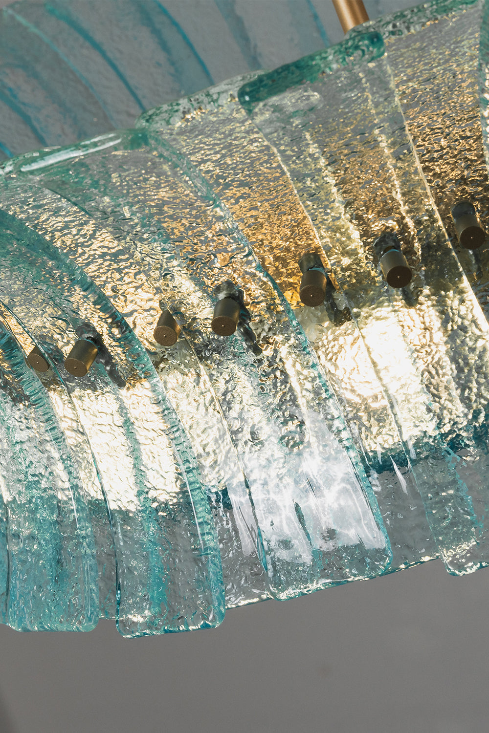 Thalassa Aquamarine Textured Glass Chandelier | Glass, Metal | Low angle shot looking up at the illuminated textured glass blocks diffusing a warm golden light through the blue-green panels | Detail shot | Samu Lamp