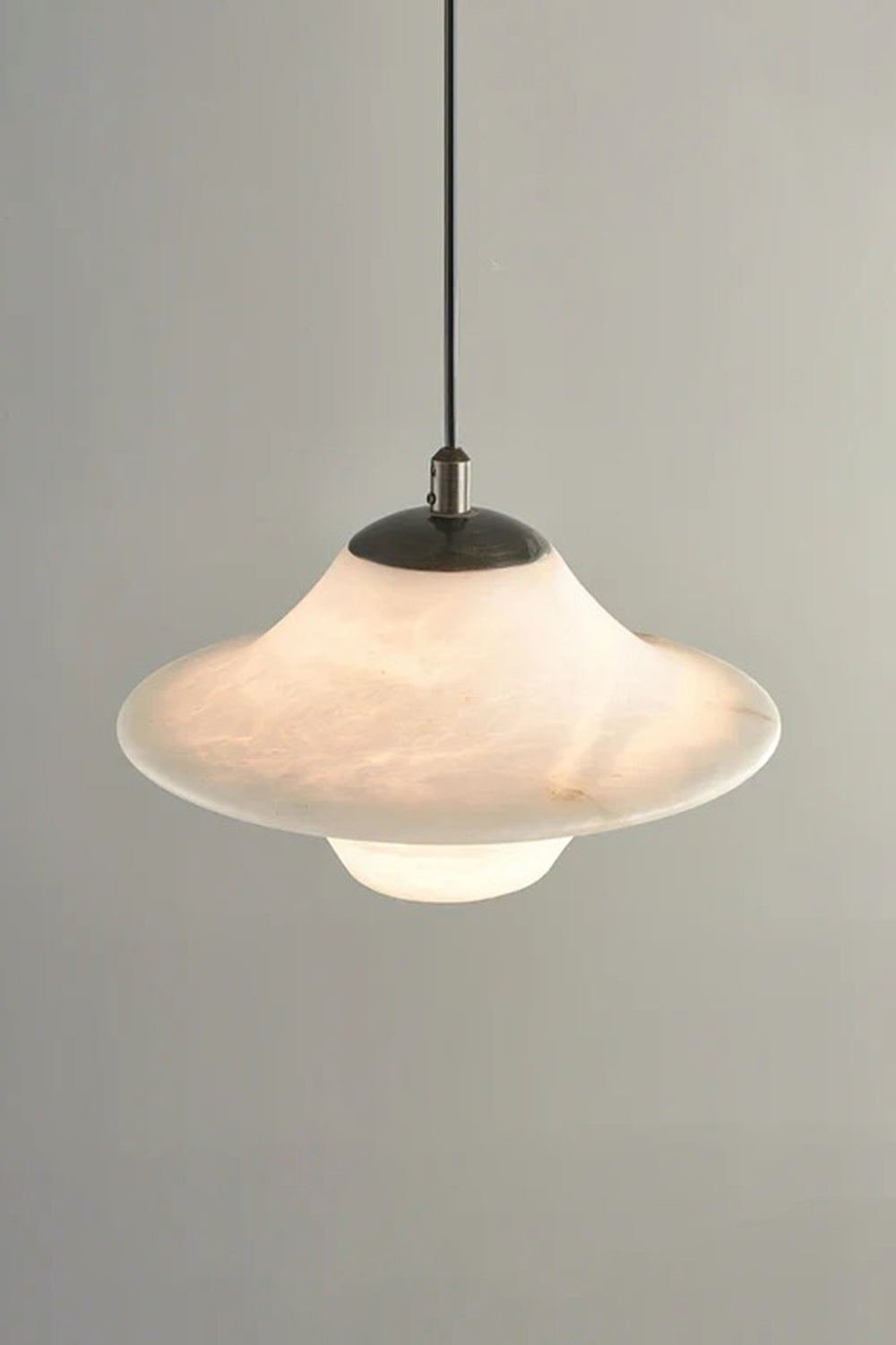 Thalia Alabaster Flared Pendant Light | Alabaster, Metal | Studio front view of the fully lit single-light flared stone pendant casting a warm ambient glow against a neutral grey background | Samu Lamp