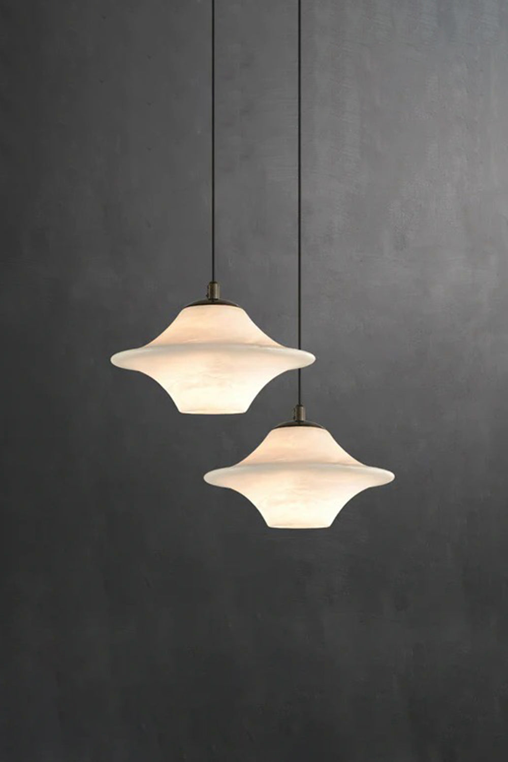 Thalia Alabaster Flared Pendant Light | Alabaster, Metal | Studio staged view of a 2-light staggered pendant combination radiating a soft warm white glow against a solid dark black background | Samu Lamp