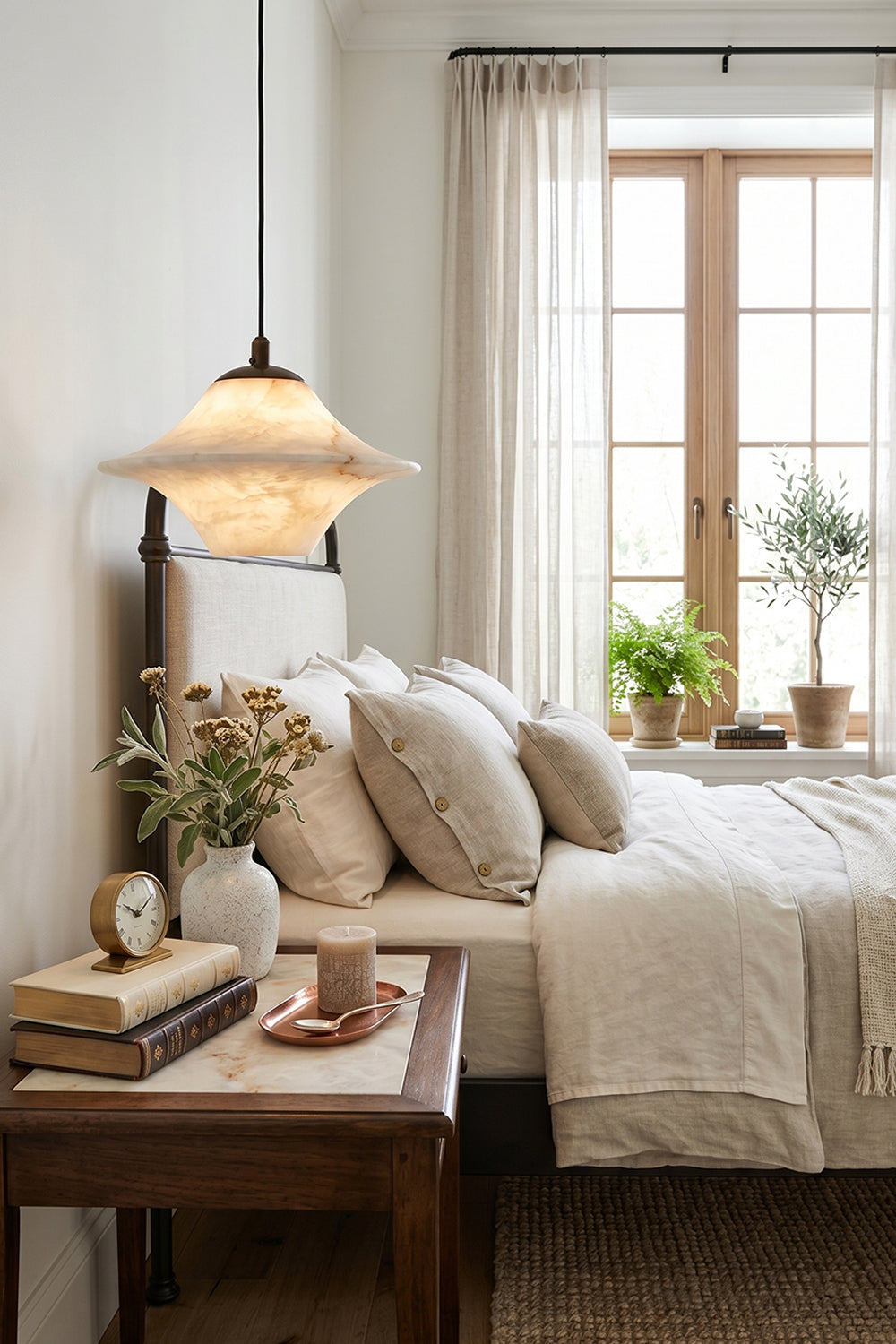 Thalia Alabaster Flared Pendant Light | Alabaster, Metal | Positioned as a low-hanging bedside accent light over a dark wood nightstand next to a comfortable cream-toned bed | Samu Lamp