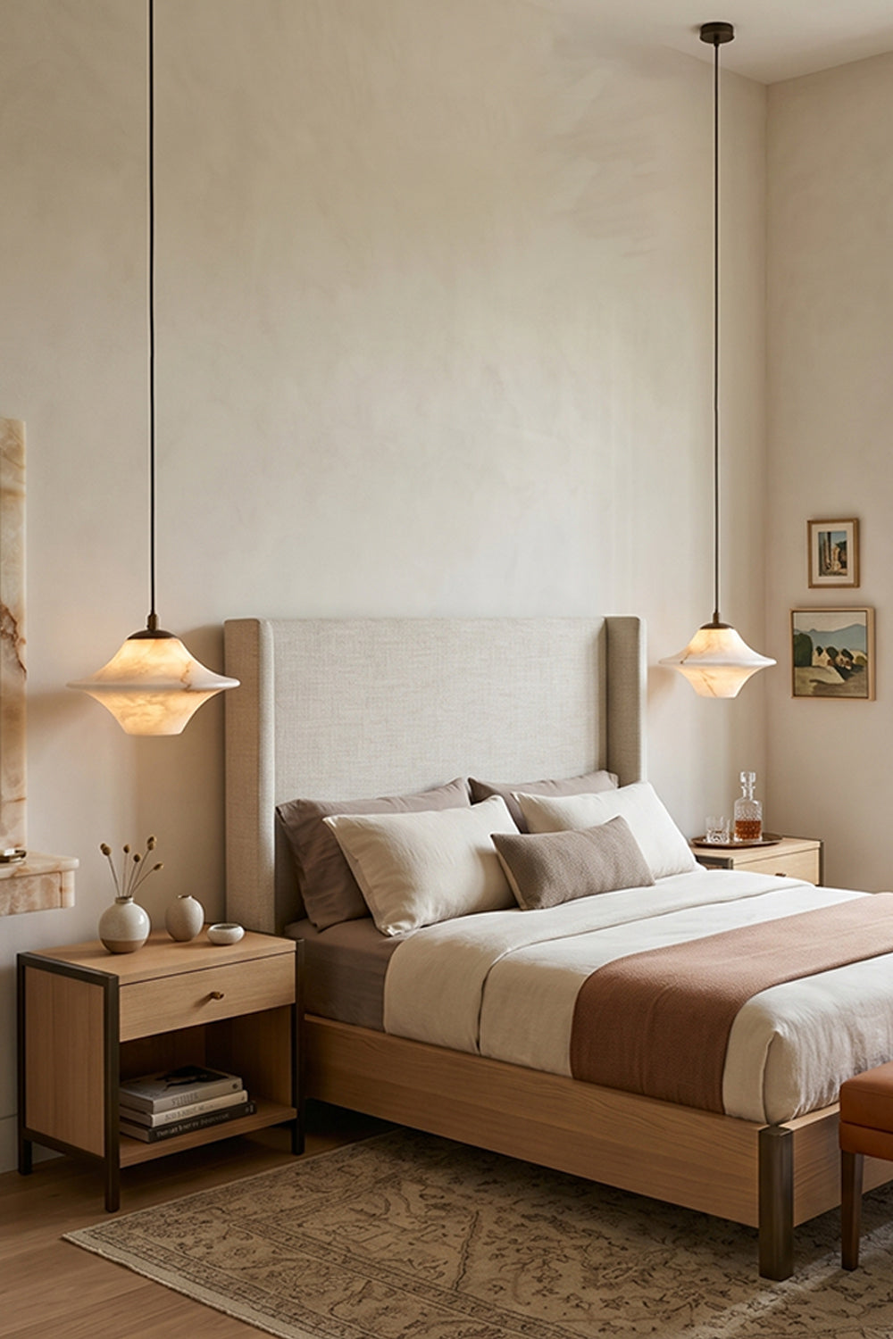 Thalia Alabaster Flared Pendant Light | Alabaster, Metal | Staged bedroom view showing a pair of lit flared stone pendants balancing either side of a bed with a tall upholstered beige headboard | Samu Lamp
