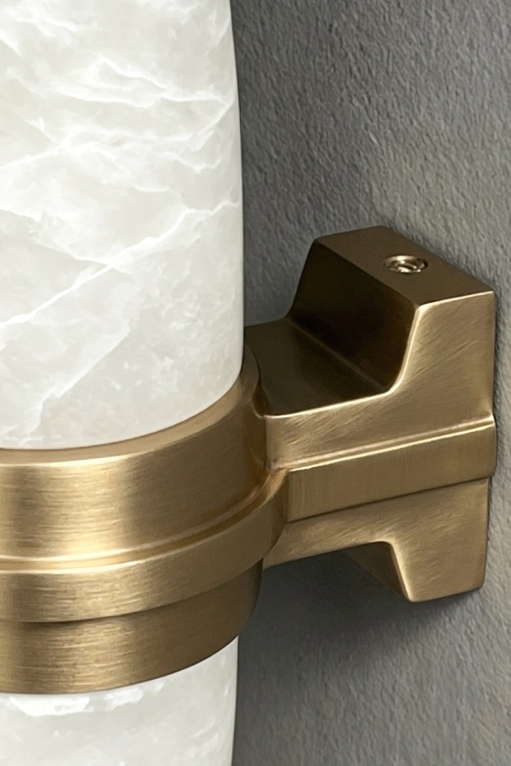 Theron Linear Alabaster Wall Lamp | Alabaster, Metal | Macro close-up view highlighting the brushed gold brass finish of the central support bracket against the natural stone veining | Detail shot | Samu Lamp