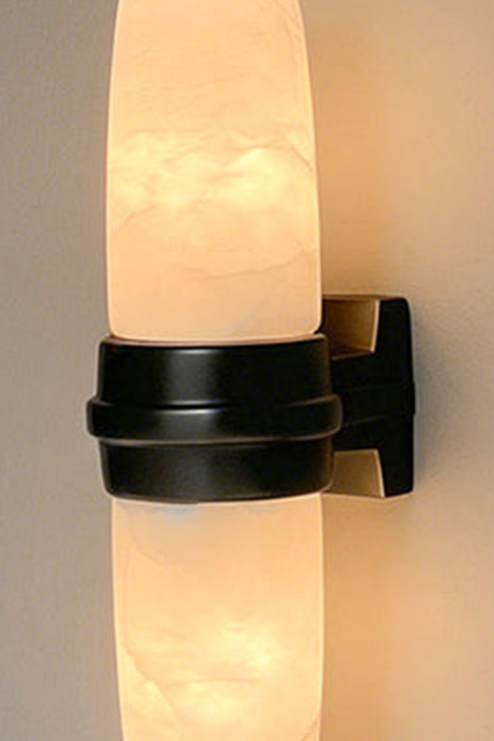 Theron Linear Alabaster Wall Lamp | Alabaster, Metal | Detailed close-up view of the lit dark base variant showcasing the soft organic clouds and lines within the stone | Detail shot | Samu Lamp