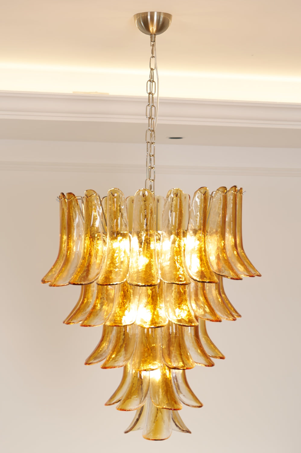 Lit Tiered Amber Lily Chandelier against plain ceiling | Metal, Glass | Side view showing warm illumination | Samu Lamp
