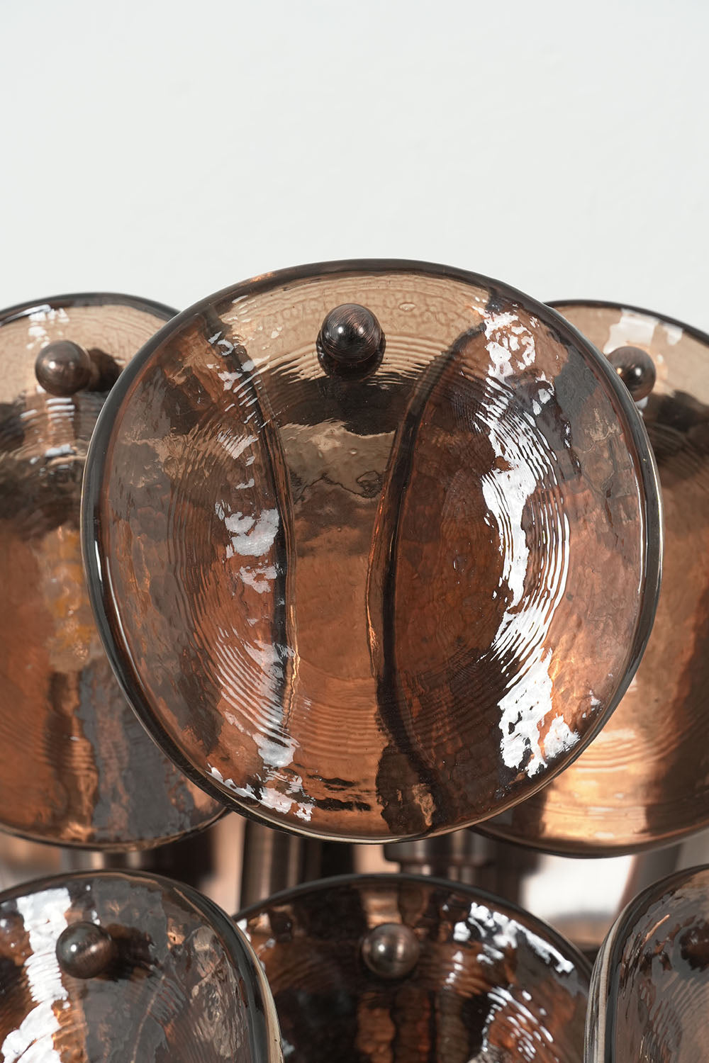 Tisanne Tiered Glass Disc Wall Lamp | Smoked Glass and Metal | Close-up front view of overlapping textured smoked glass disc layers | Samu Lamp