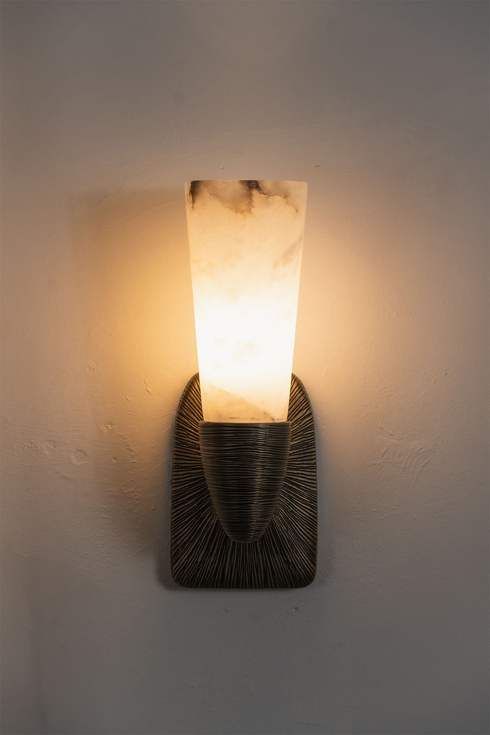 Torsanne Wall Sconce | Alabaster and Bronze | Single-light model illuminated front view on grey wall | Samu Lamp