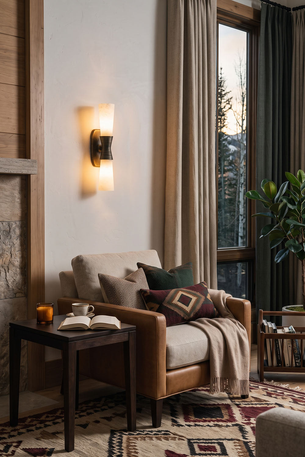 Torsanne Wall Sconce | Alabaster and Bronze | Illuminating a leather armchair corner in cozy living room | Samu Lamp