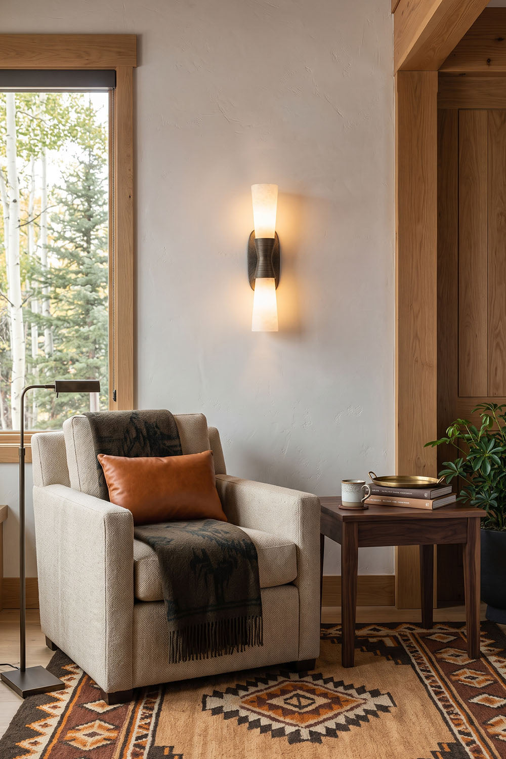 Torsanne Wall Sconce | Alabaster and Bronze | Lit above a cream armchair in bright living room corner | Samu Lamp