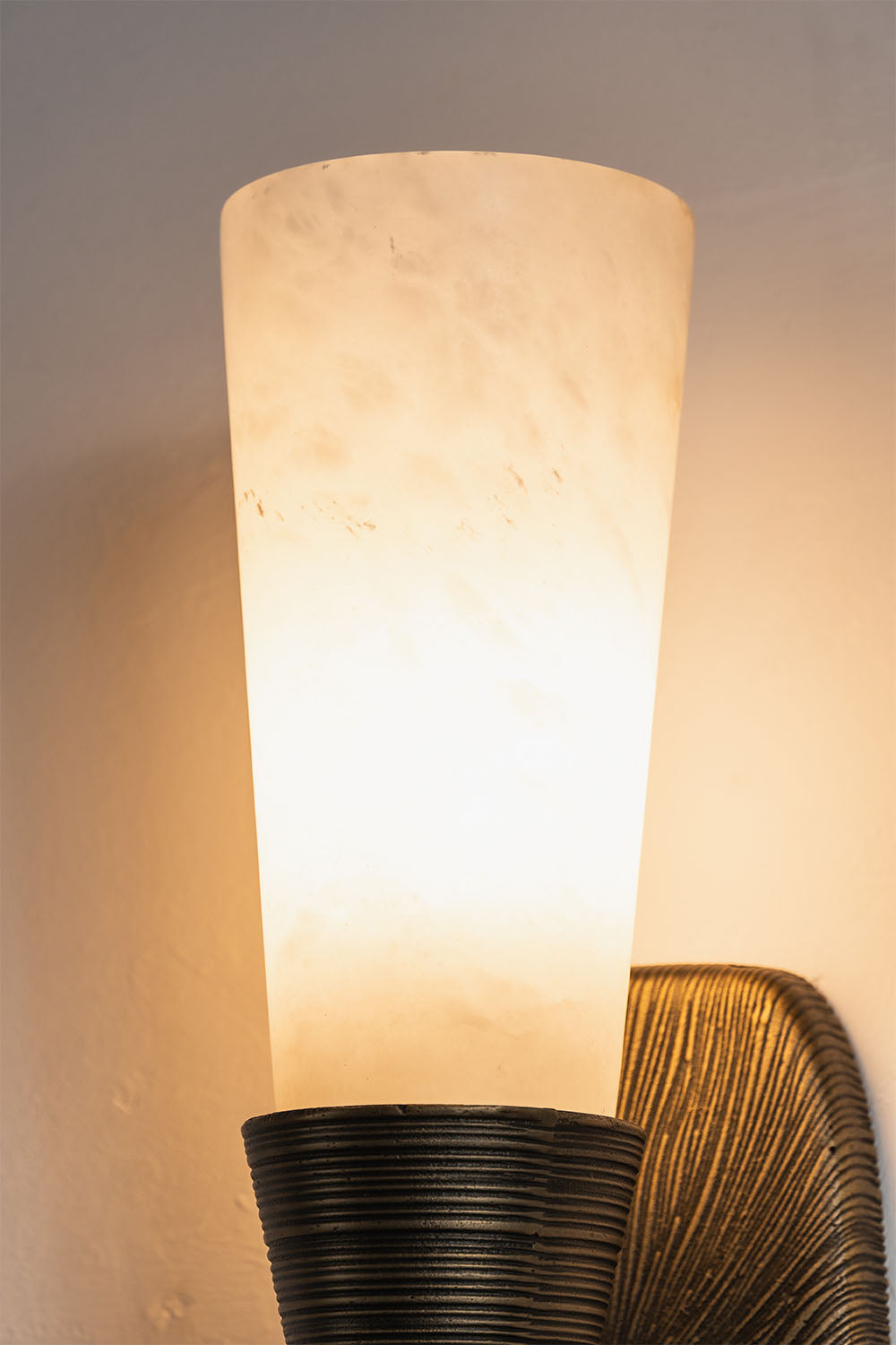 Torsanne Wall Sconce | Translucent Alabaster | Illuminated close-up of conical shade and textured base | Samu Lamp