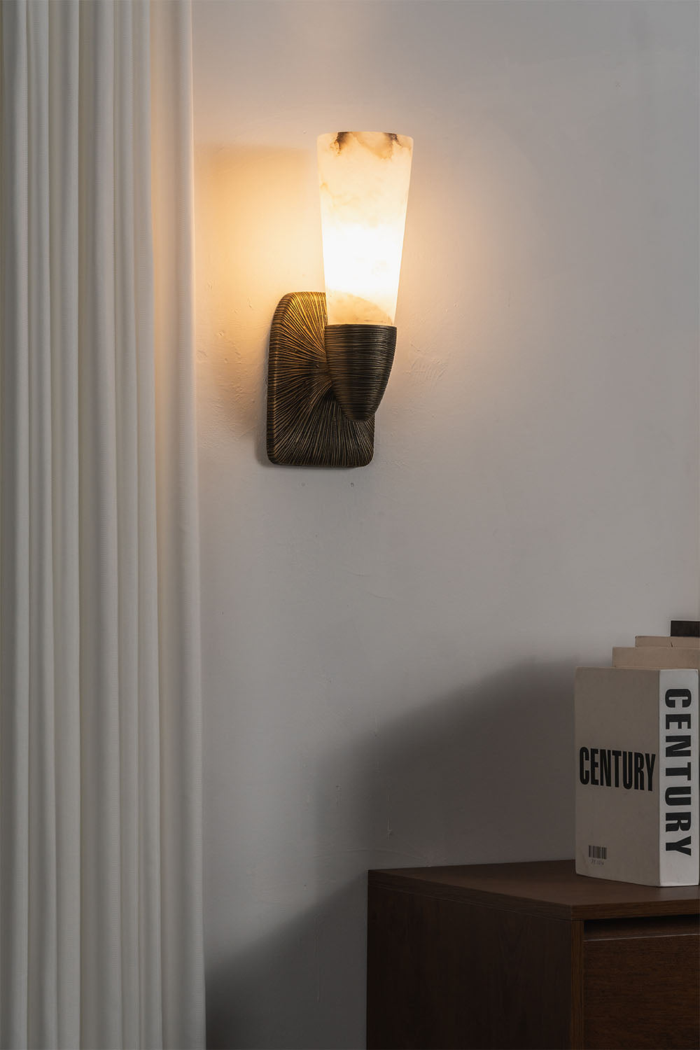 Torsanne Wall Sconce | Alabaster and Bronze | Single-light sconce lit above wooden credenza with books | Samu Lamp