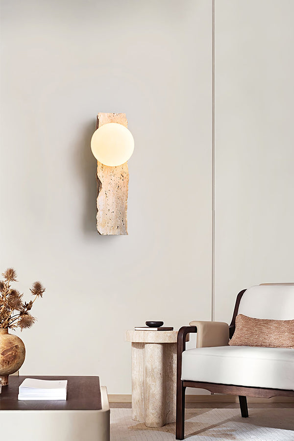 Sculptural stone wall lamp in minimalist interior | Yellow Travertine, Metal, Glass | Near a wooden armchair and decor | Samu Lamp