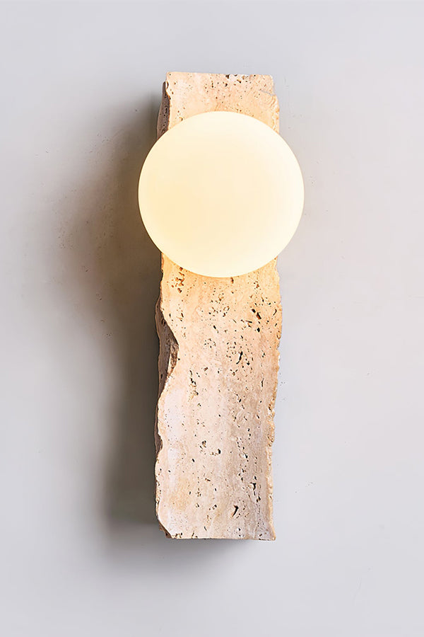 Front view of lit travertine block wall sconce | Yellow Travertine, Metal, Glass | Detailed shot against a grey studio background | Samu Lamp