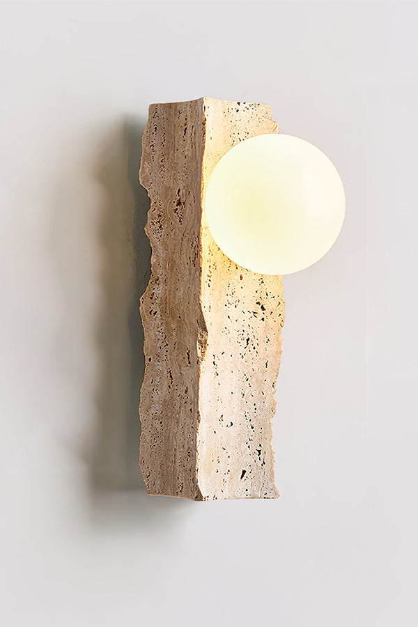 Angled perspective of lit stone block wall lamp | Yellow Travertine, Metal, Glass | Showing the warm glow and organic stone form | Samu Lamp