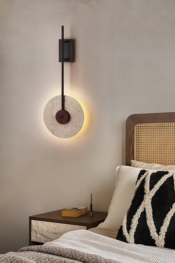 Travertine halo light in a warm bedroom setting | Travertine, Wood, Metal | Mounted near a rattan headboard and patterned pillows | Samu Lamp