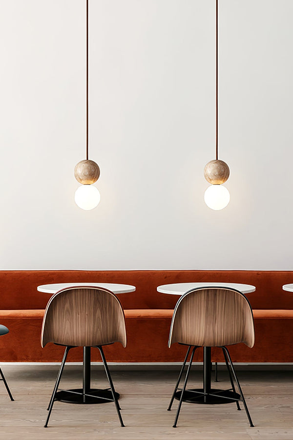 Pair of travertine stone pendants over a booth | Yellow Travertine, Glass | Installed in a restaurant or dining nook | Samu Lamp