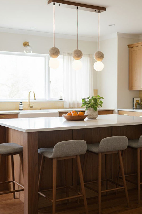 Linear travertine pendant lighting | Yellow Travertine, Glass | 3-light arrangement over a large kitchen island | Samu Lamp