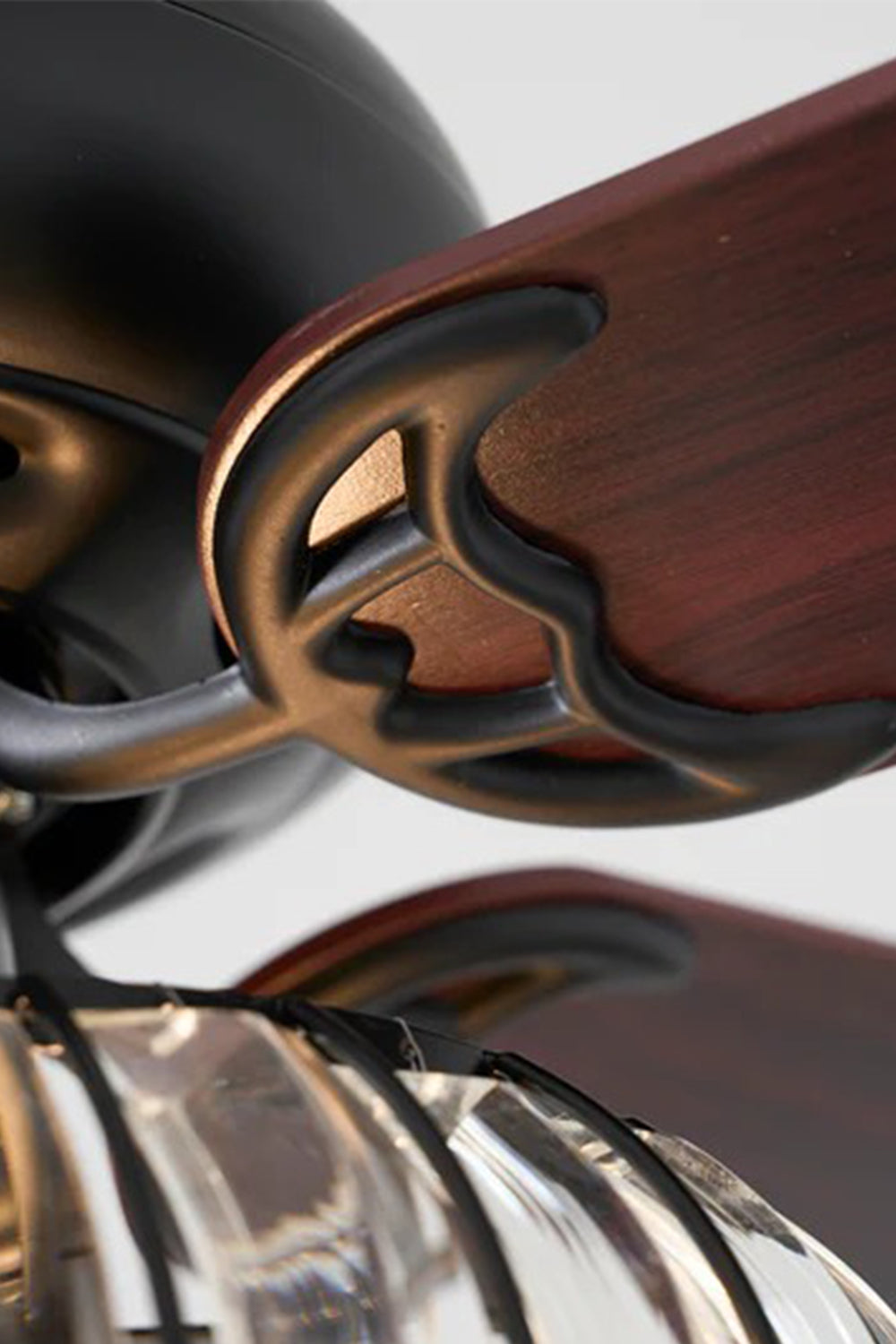 Valerius Luxury Crystal Ceiling Fan Light | Crystal, Metal, Wood | Close-up focus on the ornate antique floral carving details on the matte black blade arm brackets and dark wood grain | Detail shot | Samu Lamp
