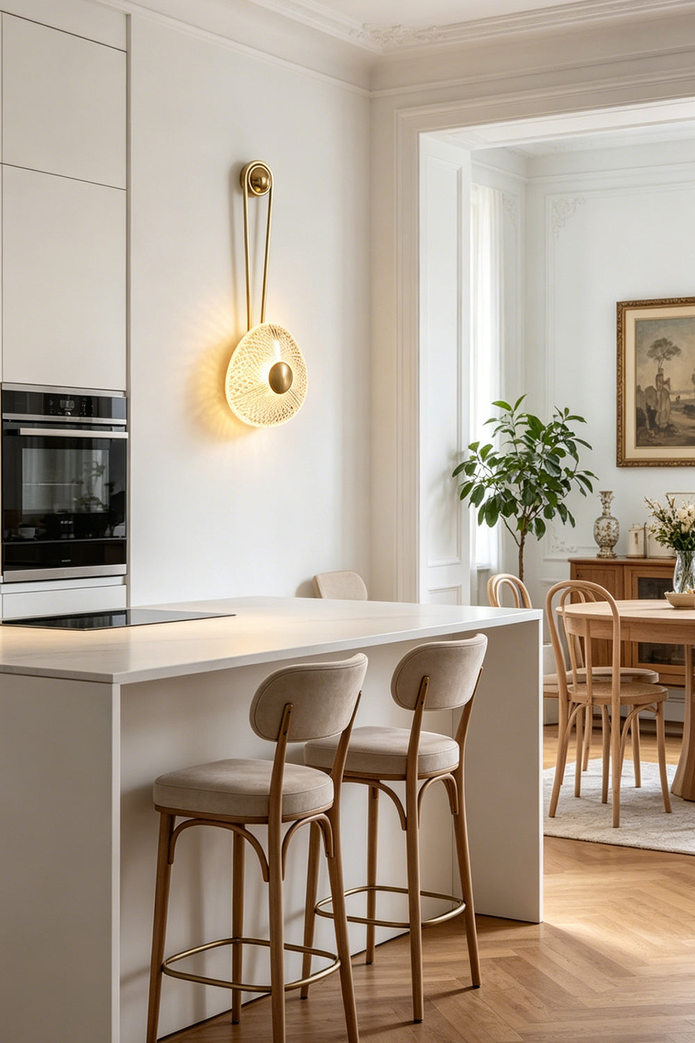Vara Aura Woven Acrylic Wall Lamp | Woven Acrylic, Brass | Styled on a kitchen wall next to a modern white kitchen island with matching upholstered bar stools | Samu Lamp
