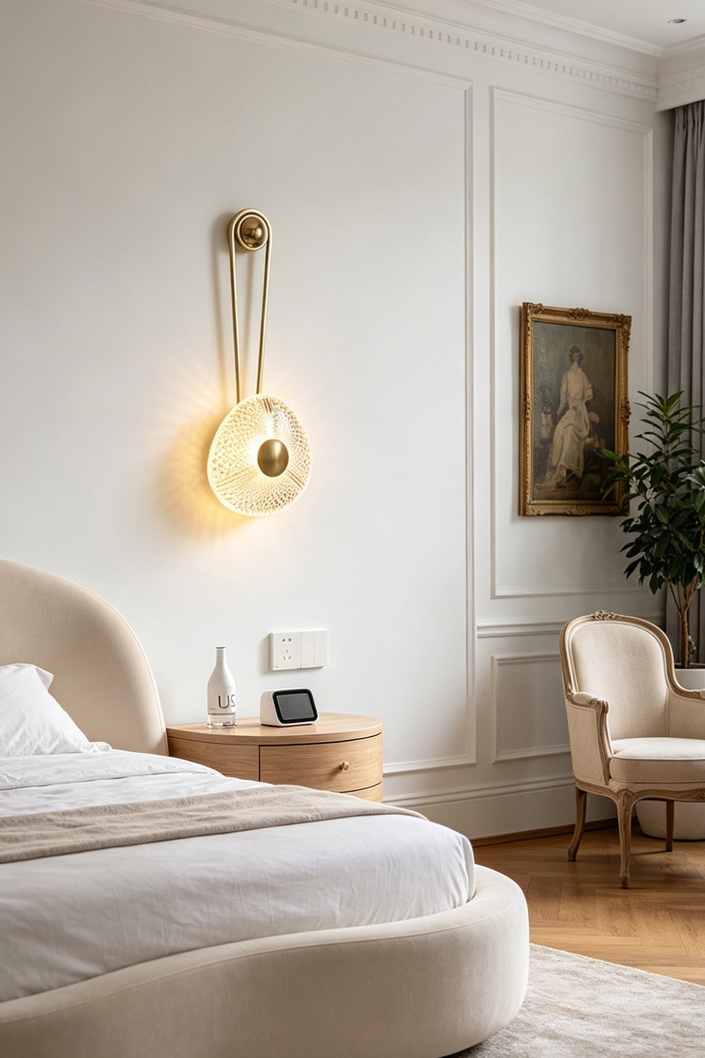 Vara Aura Woven Acrylic Wall Lamp | Woven Acrylic, Brass | Installed as an elegant bedside reading sconce on a white wall next to a bed with neutral linens | Samu Lamp