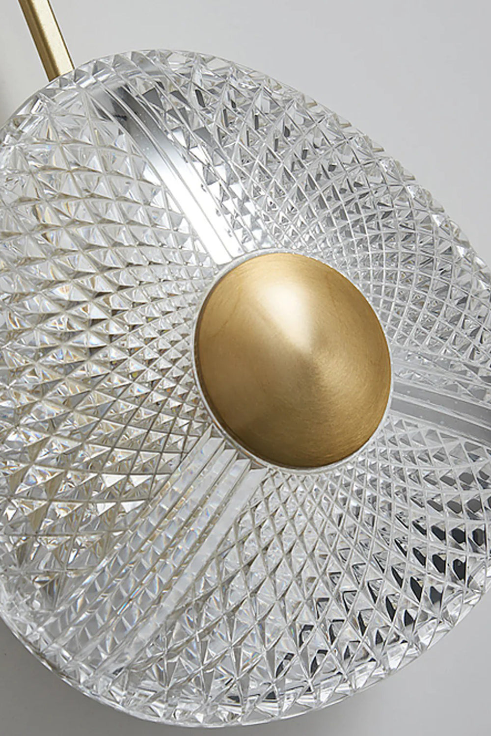Vara Aura Woven Acrylic Wall Lamp | Woven Acrylic, Brass | Close-up shot focusing on the intricate woven pattern of the clear acrylic shade and central brass disc | Samu Lamp