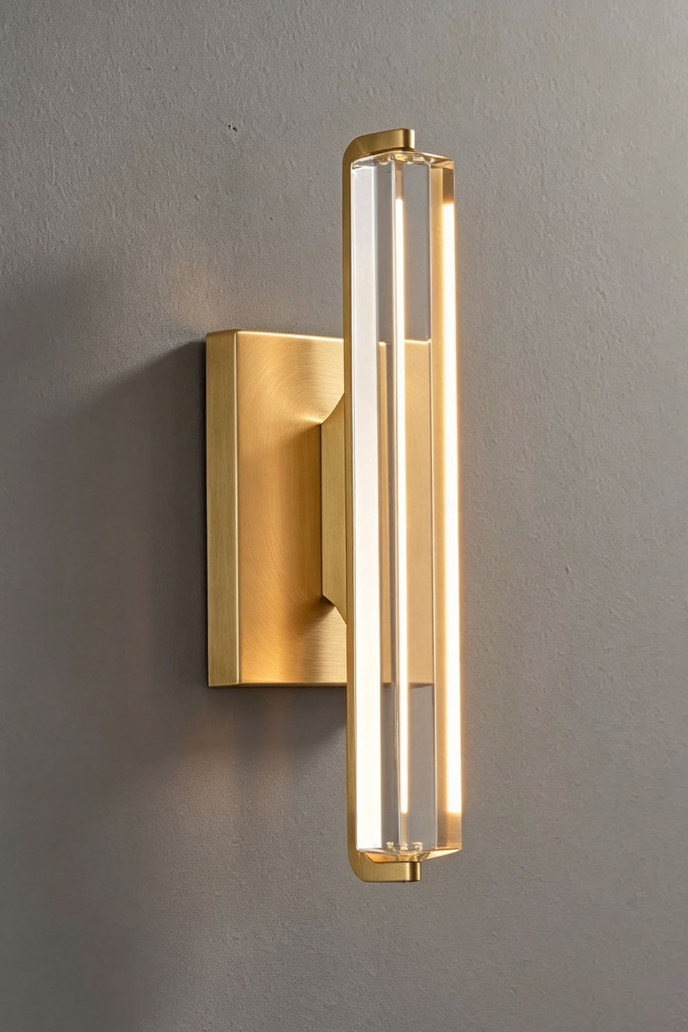 Verel Crystal Bar Wall Sconce featuring a clear crystal bar and brass frame illuminated by warm LED light.