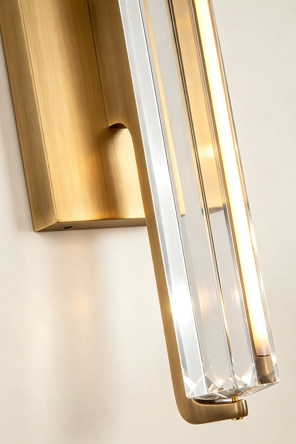 Verel Crystal Bar Wall Sconce featuring a clear crystal bar and brass frame, illuminated by integrated warm LED.