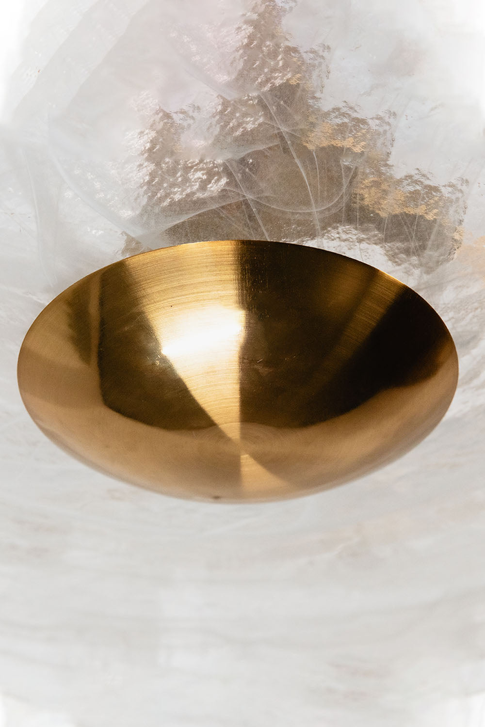 Verel Stepped Glass Drum Chandelier showcasing a sleek brass bowl detail against a textured glass backdrop.