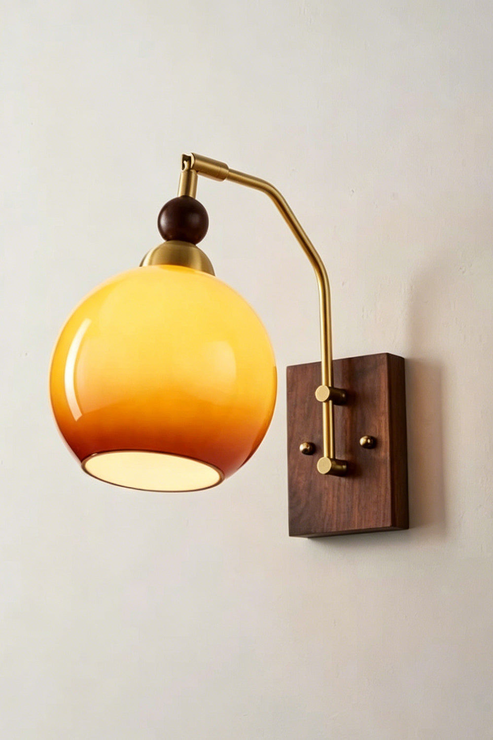 Vesper Caramel Gradient Wall Lamp | Glass, Metal, Wood | Angled view of the fully illuminated glass sconce radiating a soft golden glow against a plain white wall | Samu Lamp