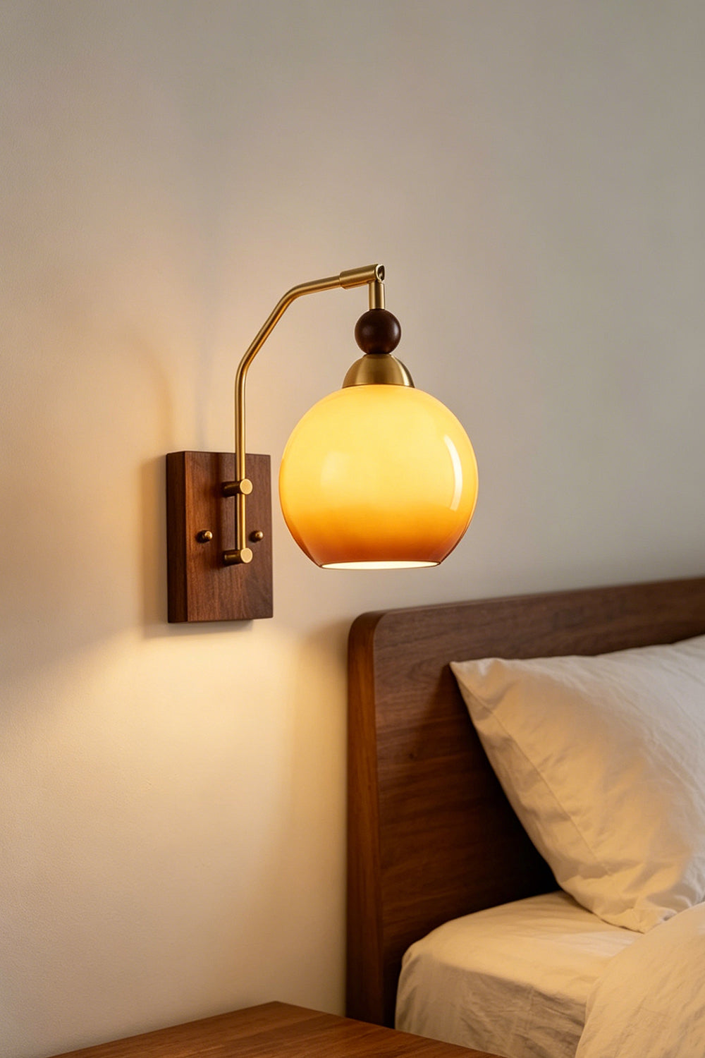 Vesper Caramel Gradient Wall Lamp | Glass, Metal, Wood | Bedside perspective of the wall sconce casting a warm, comforting light directly over a white pillow setup | Samu Lamp