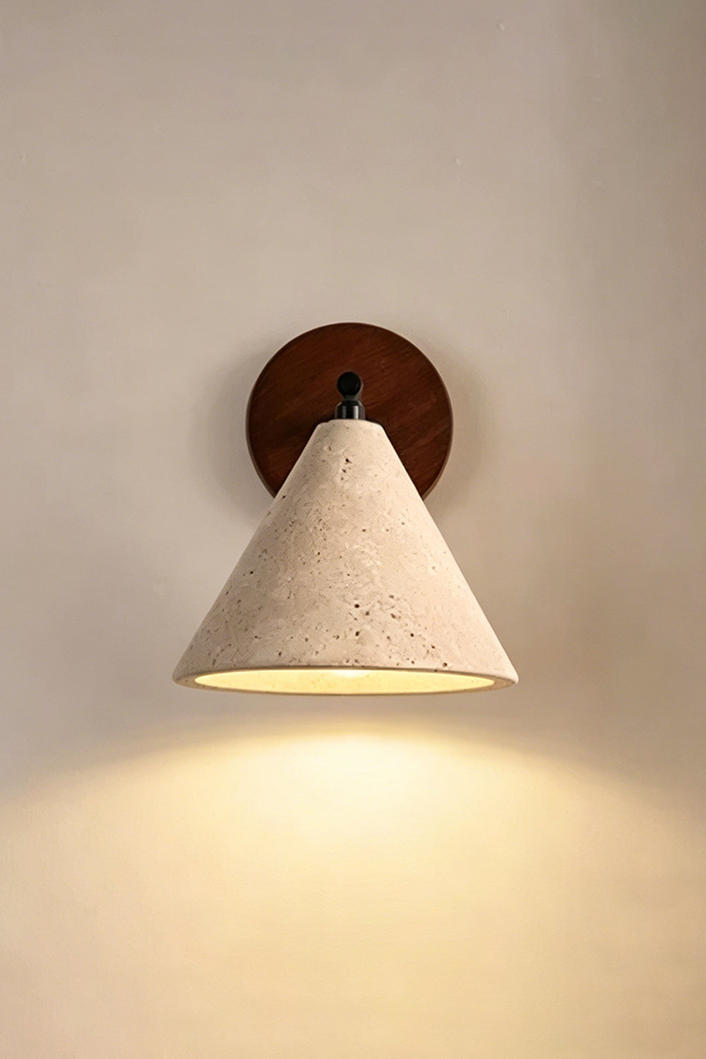 Vesper Cone Travertine Wall Light | Travertine, Wood | Lit sconce on neutral wall providing warm downlight | Samu Lamp