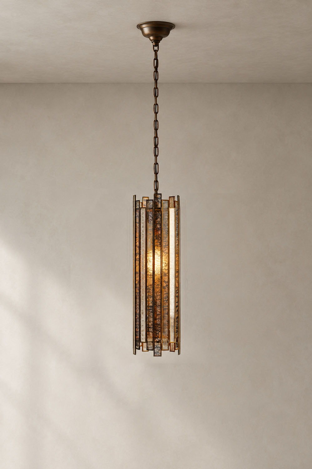 Vitrelle Cylinder Pendant | Textured Glass and Bronze | Full vertical drop view lit against wall casting shadow | Samu Lamp
